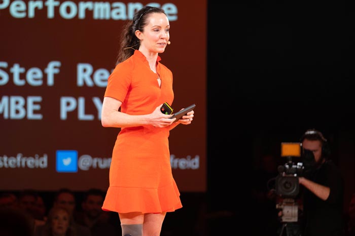 Stef Reid MBE speaking on stage at a conference